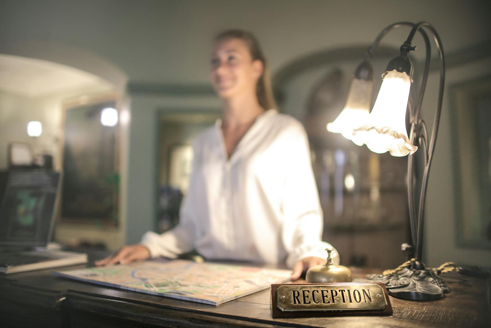 A hotel front desk concierge under ambient lighting, ready to greet an arriving guest.